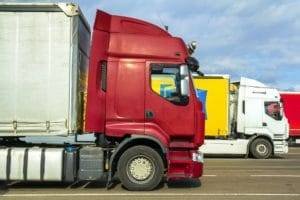 Colorful modern big semi-trucks and trailers of different makes and models stand in row on flat