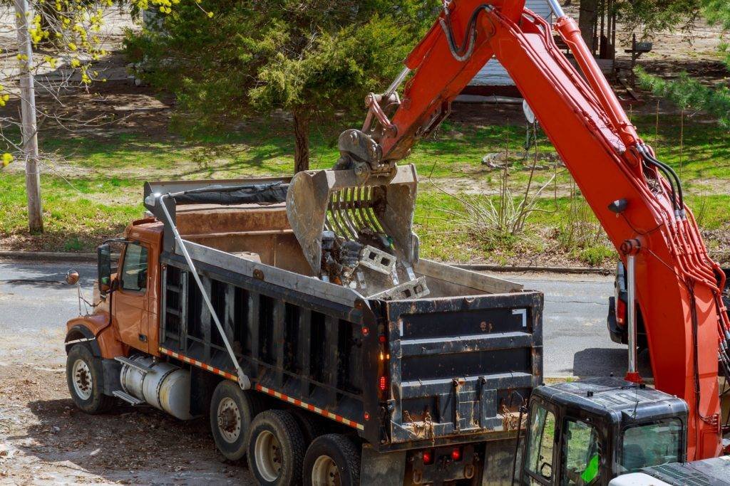 Excavator picks up construction waste for loading onto a dump truck
